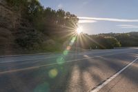 a motorcyclist with a helmet is on the road, passing the sun