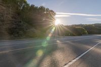 a motorcyclist with a helmet is on the road, passing the sun