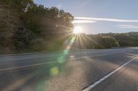 a motorcyclist with a helmet is on the road, passing the sun