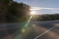 a motorcyclist with a helmet is on the road, passing the sun