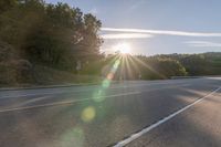 a motorcyclist with a helmet is on the road, passing the sun