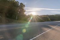 a motorcyclist with a helmet is on the road, passing the sun