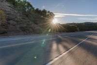 a motorcyclist with a helmet is on the road, passing the sun