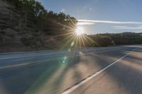 a motorcyclist with a helmet is on the road, passing the sun