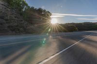 a motorcyclist with a helmet is on the road, passing the sun