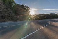 a motorcyclist with a helmet is on the road, passing the sun