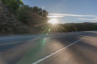 a motorcyclist with a helmet is on the road, passing the sun