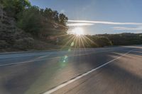 a motorcyclist with a helmet is on the road, passing the sun