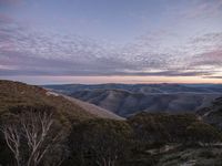 a view over some hills in the sun set with a pink sky overhead in this photograph