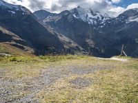 a man rides his bike up the hill next to the mountains of a mountain valley