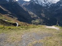 a man rides his bike up the hill next to the mountains of a mountain valley