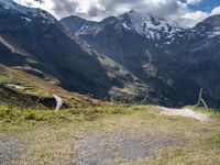 a man rides his bike up the hill next to the mountains of a mountain valley