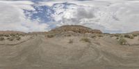 a mountain in the middle of a desert with a white cloud in the sky above