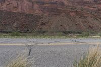 grass and shrubs surround a winding road by a mountain side in the desert area,