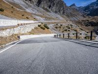 a paved highway in mountains during the day with no cars on it is steeple and the side of this road is grey in color