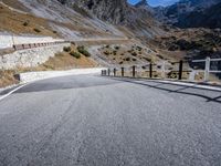 a paved highway in mountains during the day with no cars on it is steeple and the side of this road is grey in color