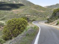 a lone motorcycle rider riding down the road in mountains behind a mountain side highway, near santa cruz