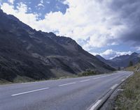 a long winding highway winding along the side of the mountains under a blue sky with clouds