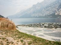 stone walkway by the beach next to water with mountains in background, at low tide