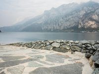 stone walkway by the beach next to water with mountains in background, at low tide