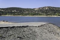 a mountain with a lake next to it in the day time and blue skies above