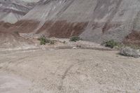 a man in yellow shirt riding on a motorcycle in the mountains, on a dirt road