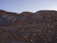 a person walking through rocks at sunset in an outdoor area with mountains and clear skies