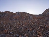 a person walking through rocks at sunset in an outdoor area with mountains and clear skies