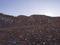 a person walking through rocks at sunset in an outdoor area with mountains and clear skies