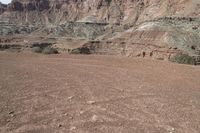 a person is standing near a rock in the desert wearing an orange jacket and blue jeans