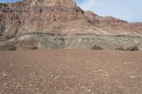 a person is standing near a rock in the desert wearing an orange jacket and blue jeans