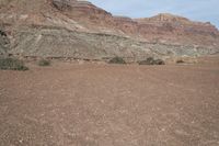 a person is standing near a rock in the desert wearing an orange jacket and blue jeans