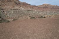 a person is standing near a rock in the desert wearing an orange jacket and blue jeans