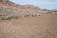 a person is standing near a rock in the desert wearing an orange jacket and blue jeans