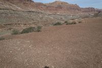 a person is standing near a rock in the desert wearing an orange jacket and blue jeans