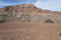 a person is standing near a rock in the desert wearing an orange jacket and blue jeans