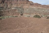 a person is standing near a rock in the desert wearing an orange jacket and blue jeans