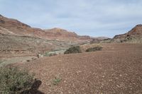 a person is standing near a rock in the desert wearing an orange jacket and blue jeans