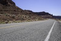 a long and narrow road going through a rocky landscape under a blue sky in the desert