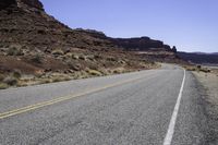 a long and narrow road going through a rocky landscape under a blue sky in the desert