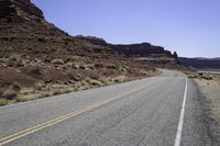 a long and narrow road going through a rocky landscape under a blue sky in the desert