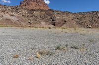 there are desert landscape with the top part of a cliff behind the grass and rocks