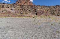 there are desert landscape with the top part of a cliff behind the grass and rocks