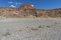 there are desert landscape with the top part of a cliff behind the grass and rocks