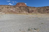 there are desert landscape with the top part of a cliff behind the grass and rocks