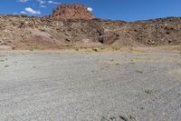 there are desert landscape with the top part of a cliff behind the grass and rocks