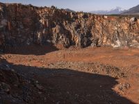 a person standing on top of a dirt field in front of a mountain and holding up something