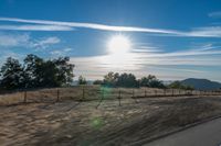 a sun shines brightly behind a wire fence in this photo from inside a car