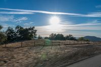 a sun shines brightly behind a wire fence in this photo from inside a car