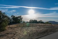 a sun shines brightly behind a wire fence in this photo from inside a car